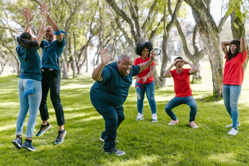 Diverse group enjoying team building games outdoors with joyful expressions.
