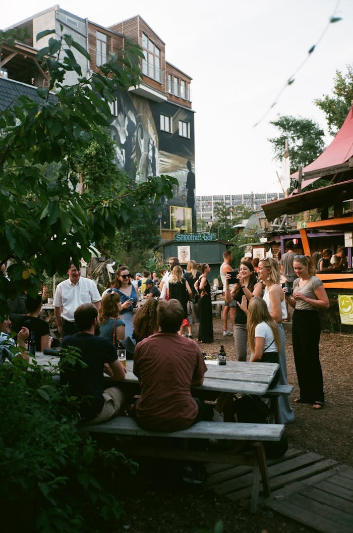 Lively outdoor gathering at a trendy urban spot with people socializing and enjoying drinks.